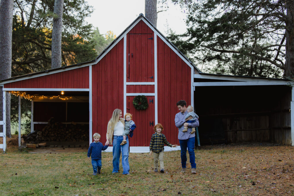  a family photo session with a red barn in the background