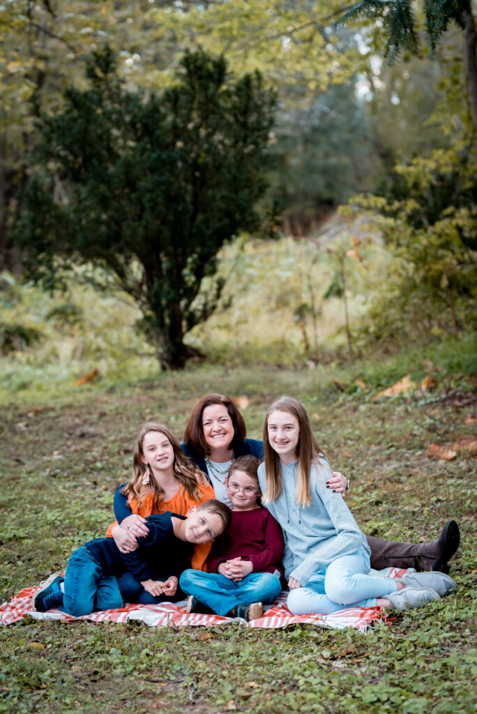 A mom sitting on a blanket with her four children being photographed for a fall mini session richmond VA